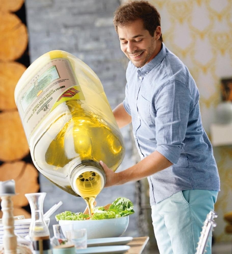 Guy pouring olive oil on the salad